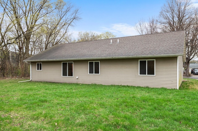 back of property with a lawn and roof with shingles