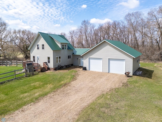 view of front of property featuring driveway, metal roof, a front yard, an attached garage, and fence