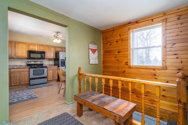 kitchen featuring crown molding, wood walls, stainless steel appliances, light brown cabinetry, and a ceiling fan