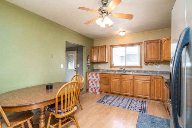 kitchen featuring ornamental molding, light wood finished floors, a sink, and freestanding refrigerator