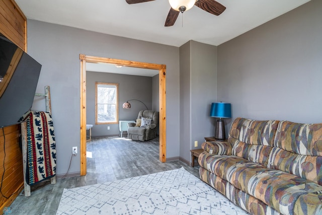 living area with a ceiling fan, wood finished floors, and baseboards