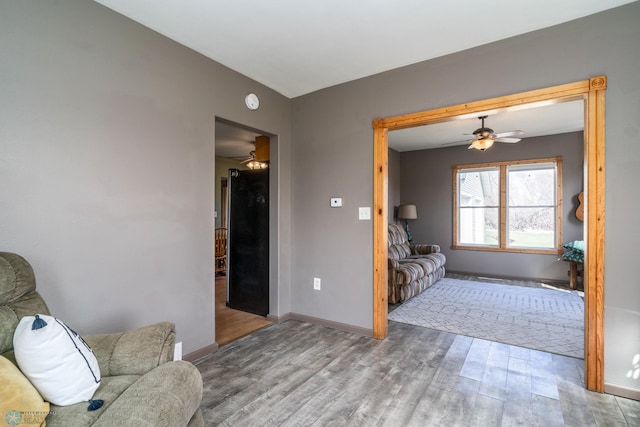 living room featuring ceiling fan, wood finished floors, and baseboards