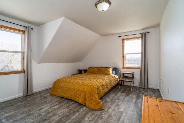 bedroom with vaulted ceiling, wood finished floors, and baseboards