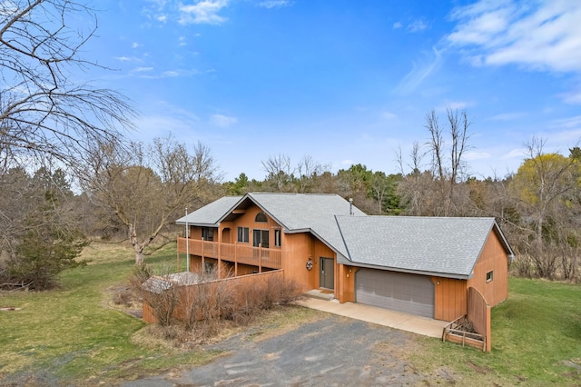 rustic home featuring a shingled roof, driveway, a balcony, a front yard, and an attached garage