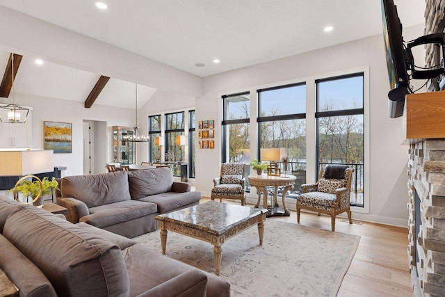 living room with a stone fireplace, an inviting chandelier, recessed lighting, and light wood-style flooring