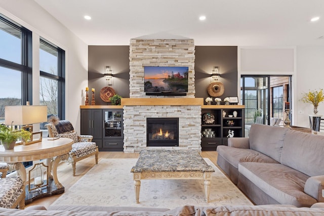 living area featuring a stone fireplace, recessed lighting, and wood finished floors