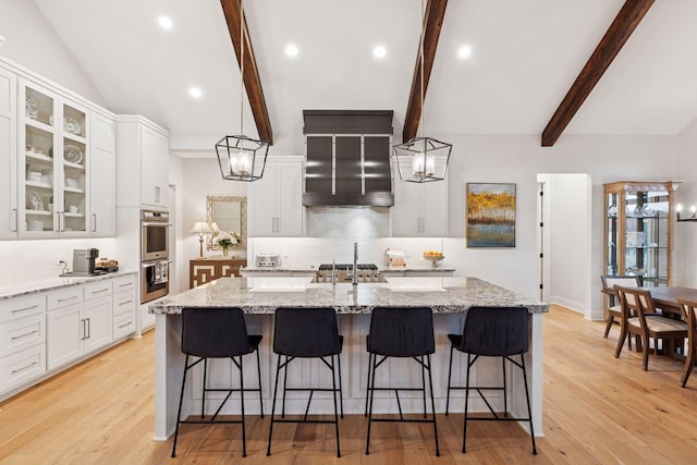 kitchen featuring stainless steel double oven, white cabinetry, a kitchen bar, decorative backsplash, and vaulted ceiling with beams