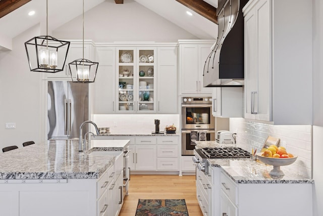 kitchen with light wood-style flooring, stainless steel appliances, a notable chandelier, white cabinets, and backsplash