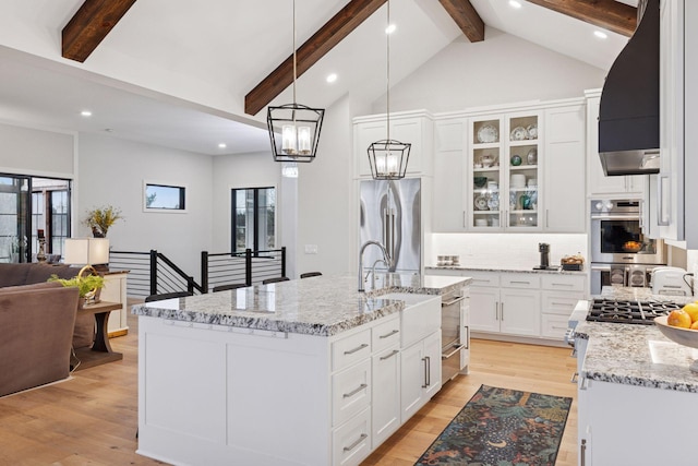 kitchen featuring backsplash, light wood finished floors, appliances with stainless steel finishes, and custom range hood