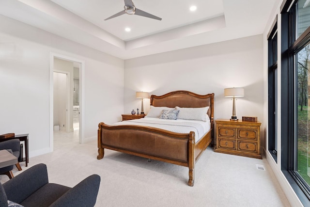 bedroom with multiple windows, light carpet, a tray ceiling, and visible vents