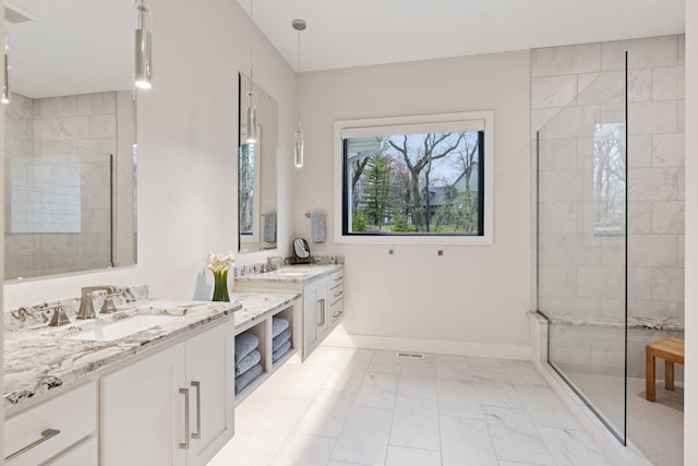 bathroom featuring marble finish floor, a walk in shower, two vanities, and a sink