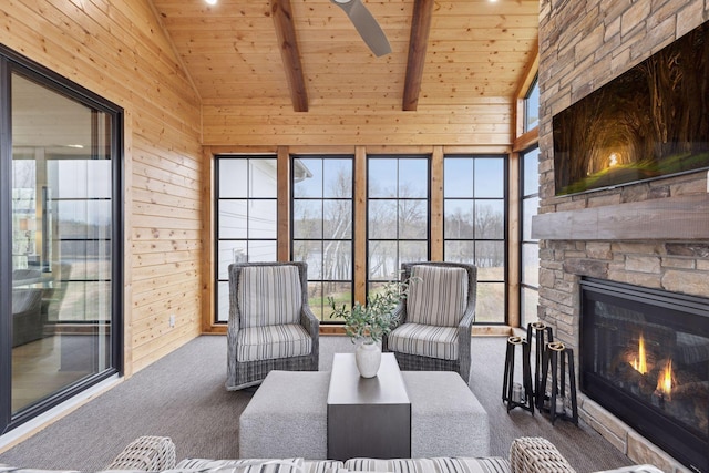carpeted living area with ceiling fan, an outdoor stone fireplace, wood walls, and wood ceiling