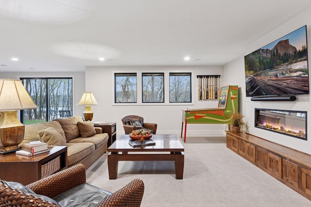 carpeted living area featuring a glass covered fireplace and recessed lighting