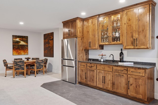 kitchen with freestanding refrigerator, recessed lighting, brown cabinets, and a sink