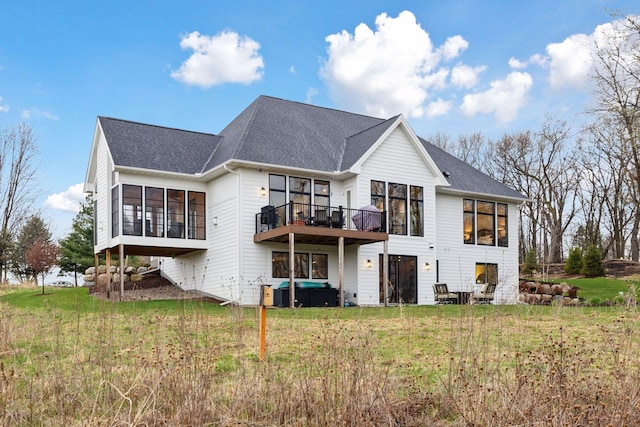 rear view of property with a yard, a sunroom, and a shingled roof