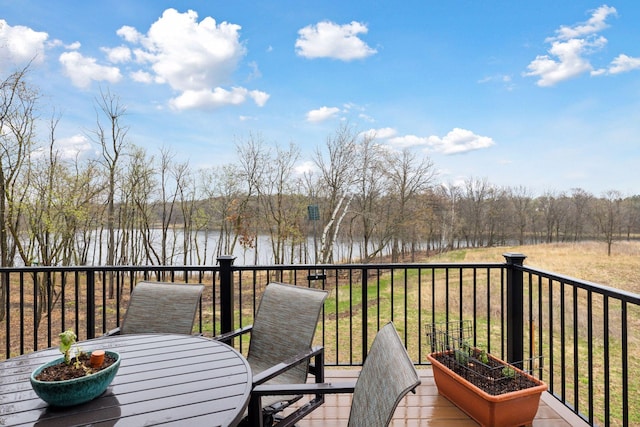 deck with a water view and outdoor dining area