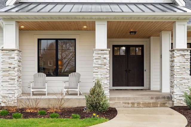 property entrance with a porch, metal roof, a standing seam roof, and stone siding