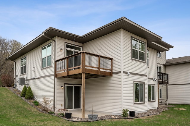 rear view of house with cooling unit, a patio area, a wooden deck, and a lawn
