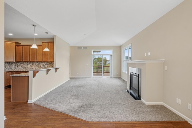 unfurnished living room featuring baseboards, a glass covered fireplace, visible vents, and wood finished floors