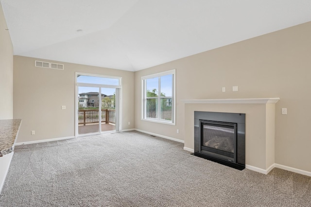 unfurnished living room featuring baseboards, carpet flooring, and vaulted ceiling