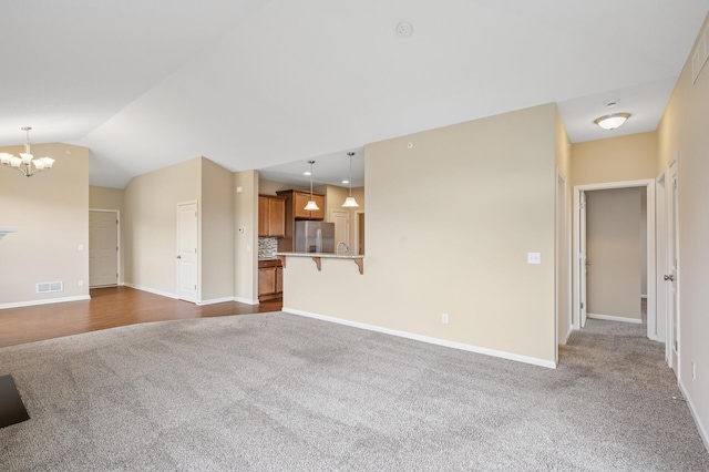 unfurnished living room featuring a chandelier, dark colored carpet, baseboards, and visible vents