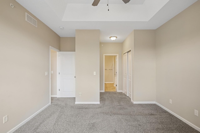 unfurnished bedroom with a closet, visible vents, ceiling fan, carpet floors, and baseboards
