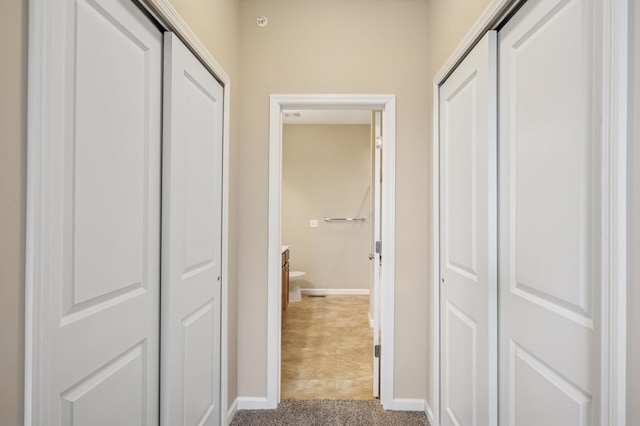 hall featuring carpet flooring and baseboards
