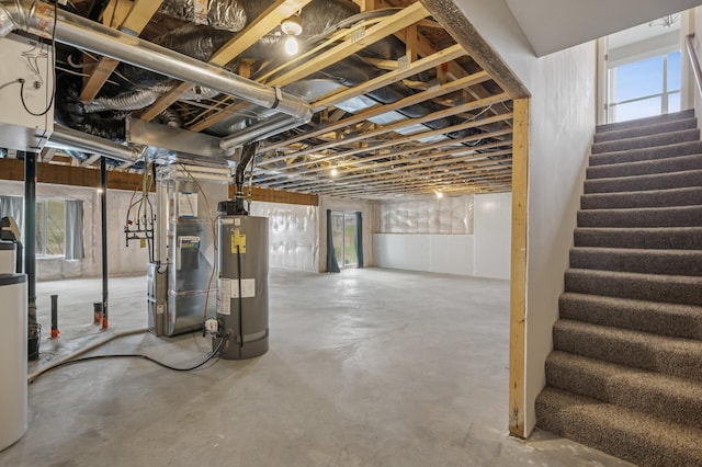 basement featuring heating unit, water heater, and stairway