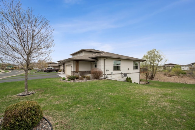 view of front facade featuring a front lawn, driveway, an attached garage, and stone siding