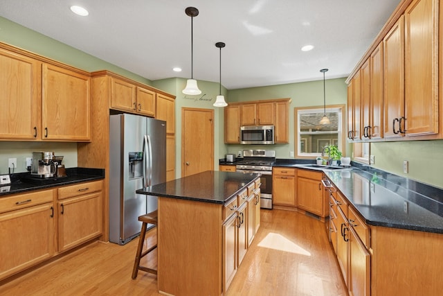813 Quie Ln, Northfield, MN 55057 - kitchen featuring appliances with stainless steel finishes, light wood finished floors, a kitchen island, a kitchen breakfast bar, and recessed lighting