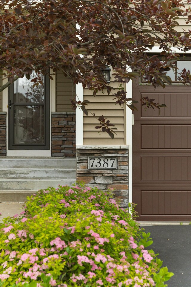 7387 Old Mill Rd, Centerville, MN 55038 - doorway to property with stone siding and a garage