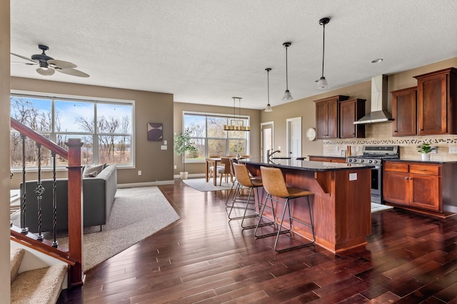 7387 Old Mill Rd, Centerville, MN 55038 - kitchen featuring wall chimney range hood, stainless steel gas range oven, dark countertops, ceiling fan, and dark wood-style flooring