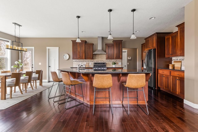 7387 Old Mill Rd, Centerville, MN 55038 - kitchen featuring stainless steel appliances, wall chimney range hood, backsplash, dark wood-type flooring, and a center island with sink