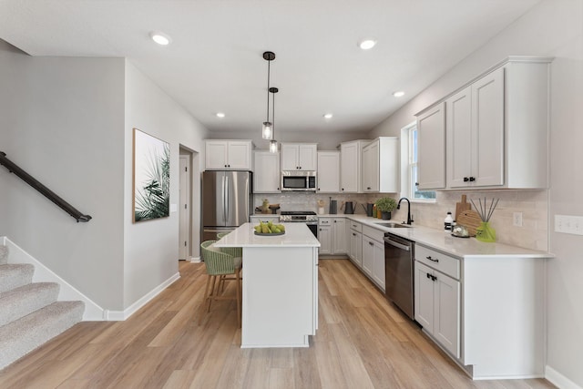 kitchen featuring a kitchen bar, a sink, light wood finished floors, backsplash, and stainless steel appliances