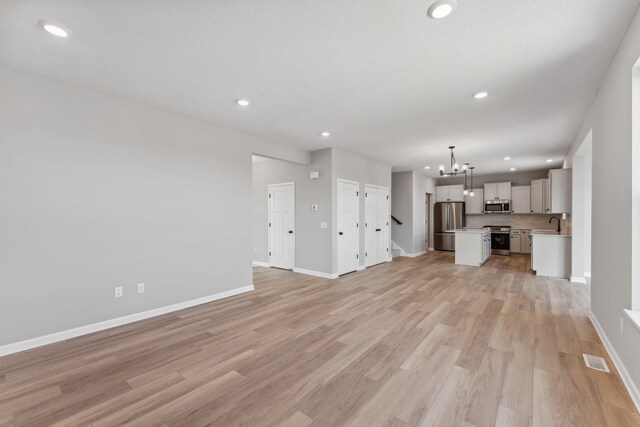 unfurnished living room featuring recessed lighting, a notable chandelier, and visible vents