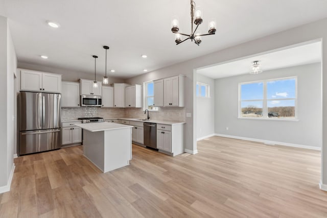 kitchen featuring a notable chandelier, light countertops, stainless steel appliances, baseboards, and decorative backsplash