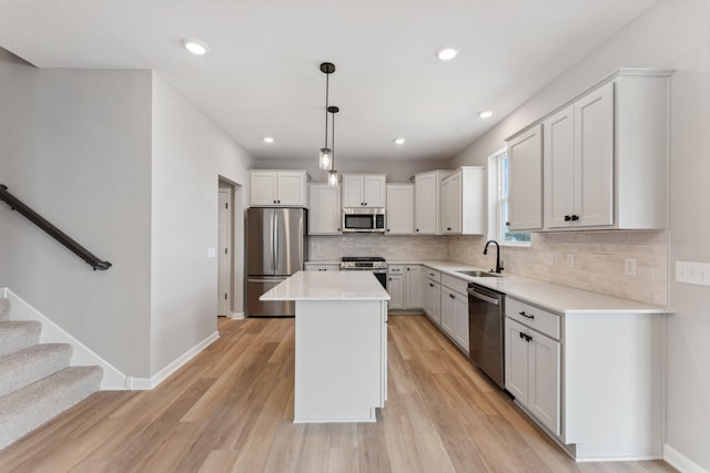 kitchen featuring a sink, light wood finished floors, a center island, stainless steel appliances, and backsplash
