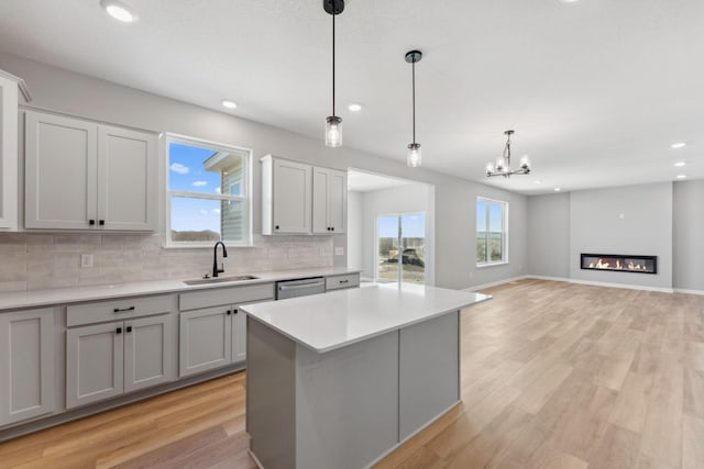 kitchen featuring backsplash, stainless steel dishwasher, a sink, light countertops, and recessed lighting