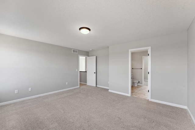 unfurnished bedroom featuring baseboards, carpet, ensuite bath, and visible vents