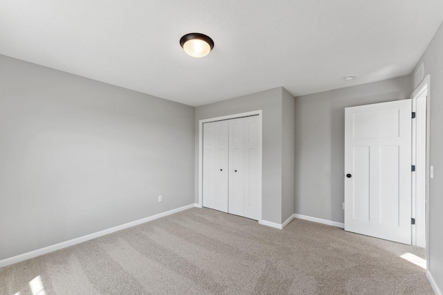 unfurnished bedroom with baseboards, carpet, and a closet