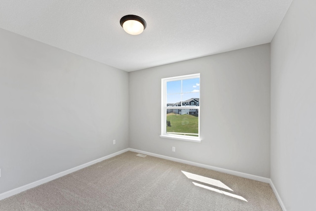 carpeted spare room with baseboards and a textured ceiling