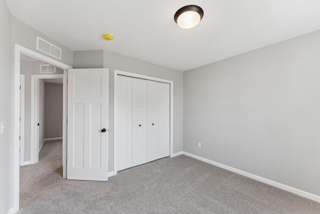 unfurnished bedroom featuring carpet floors, baseboards, visible vents, and a closet