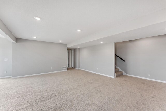 finished basement featuring baseboards, stairs, and light colored carpet