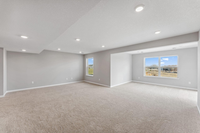 spare room featuring recessed lighting, baseboards, light colored carpet, and plenty of natural light