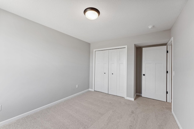 unfurnished bedroom featuring baseboards, carpet, and a closet