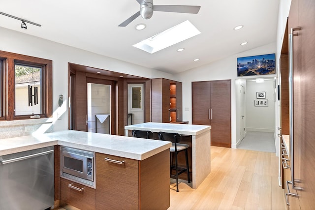 4721 Lake Harriet Pkwy, Minneapolis, MN 55419 - kitchen featuring appliances with stainless steel finishes, modern cabinets, a skylight, a breakfast bar area, and light wood-style floors