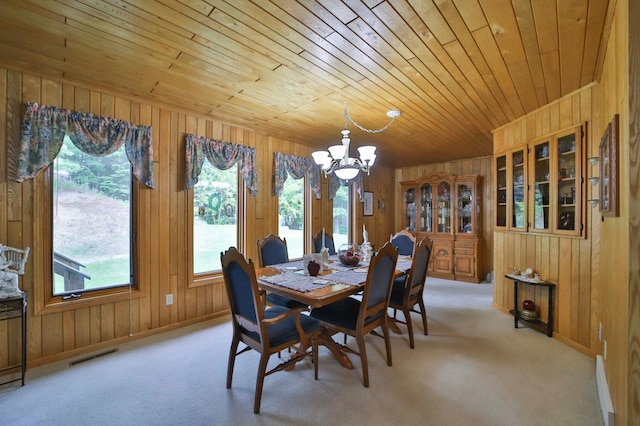7717 Lake May Rd NW, Walker, MN 56433 - dining area with a chandelier, wooden walls, wood ceiling, light colored carpet, and baseboards