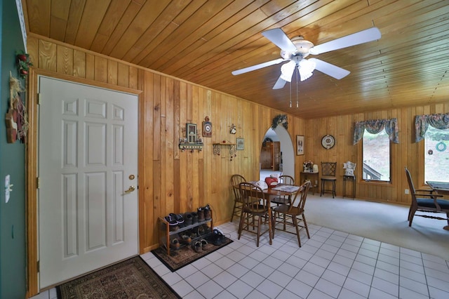 7717 Lake May Rd NW, Walker, MN 56433 - carpeted dining space featuring arched walkways, wood ceiling, wooden walls, a ceiling fan, and tile patterned flooring