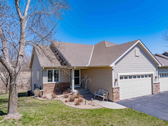 view of front of home with a garage, aphalt driveway, a front yard, stone siding, and roof with shingles