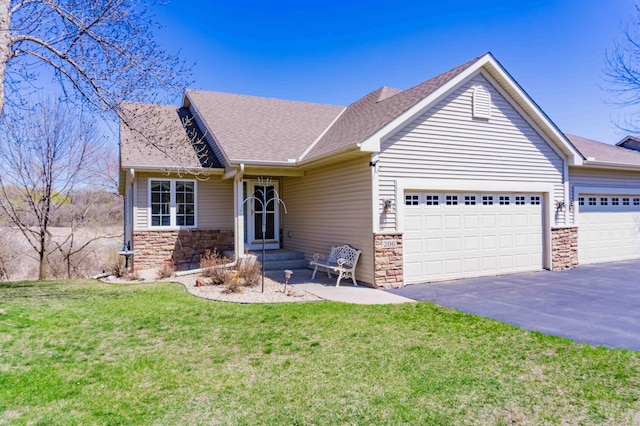 view of front of home featuring a front yard, an attached garage, stone siding, and aphalt driveway